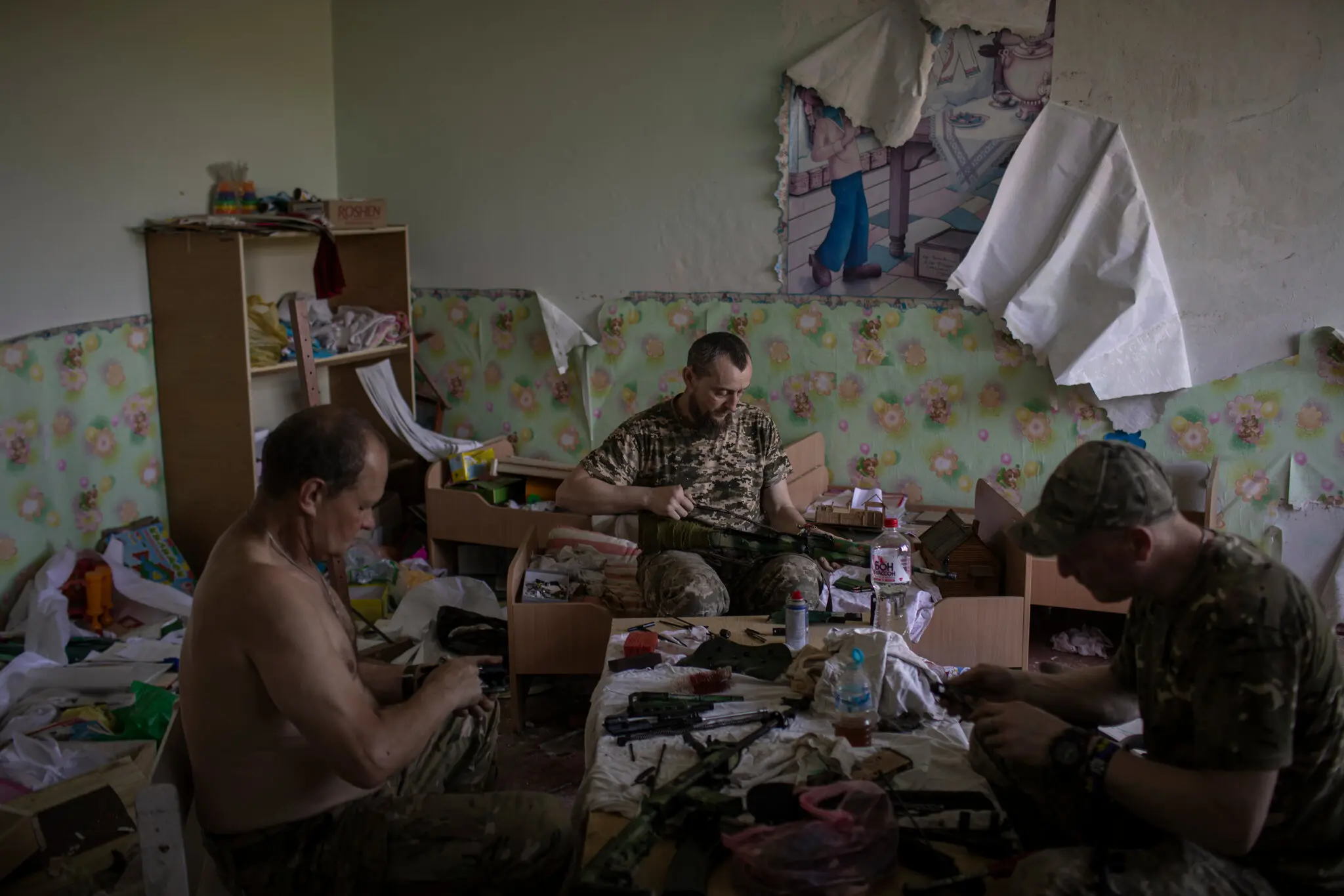 Бійці 129-ї бригади територіальної оборони чистять та готують зброю в дитячому садку на південному фронті.